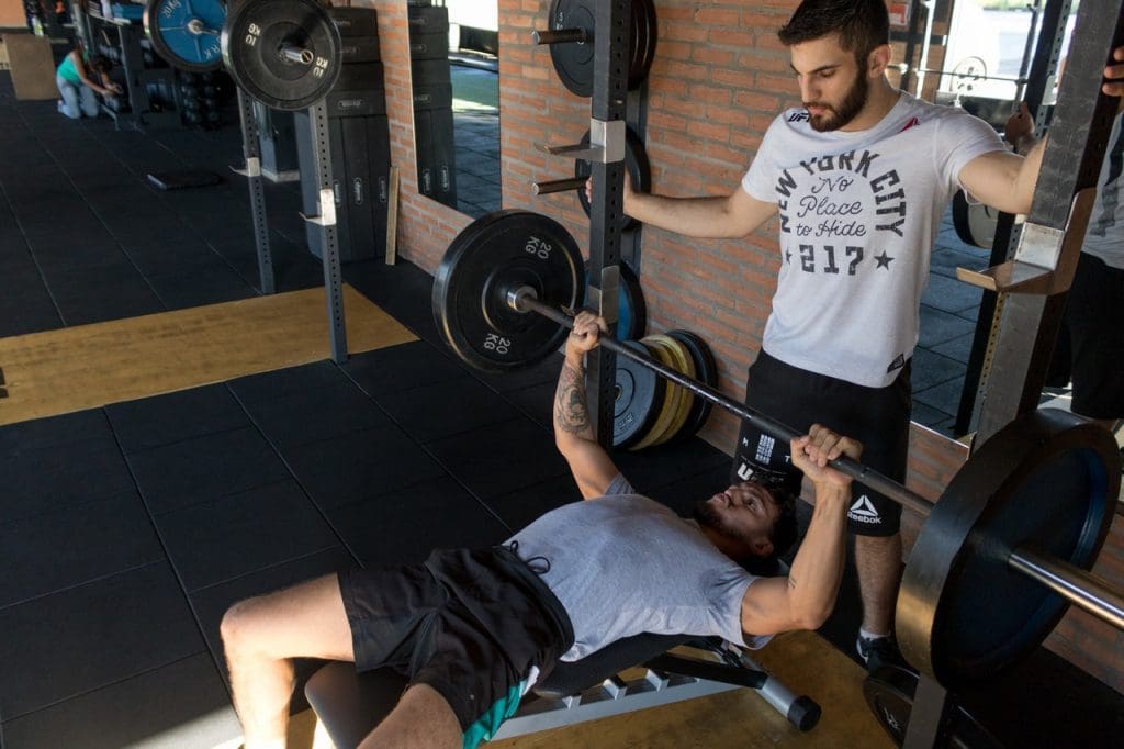 Personal trainer helping lift weights